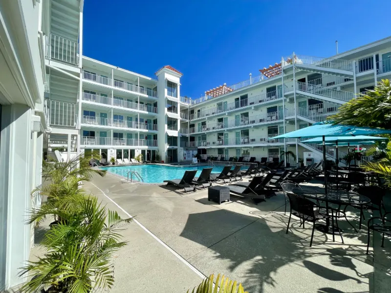 The Aqua Beach Hotel pool courtyard with lounge chairs, palm trees and teal umbrellas