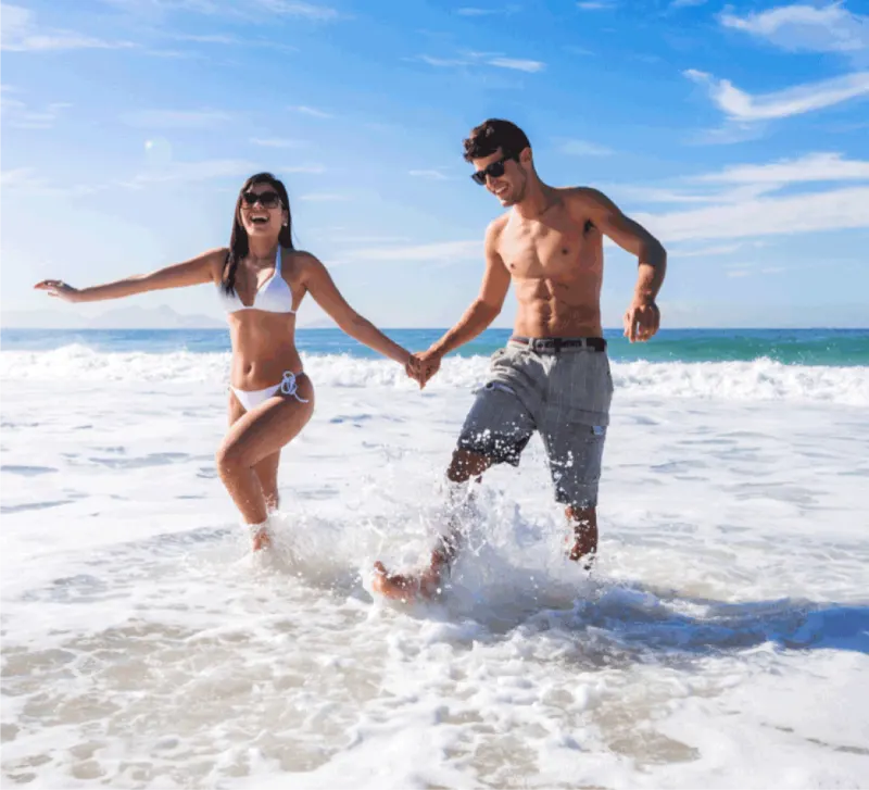 A couple laughing and splashing through the surf